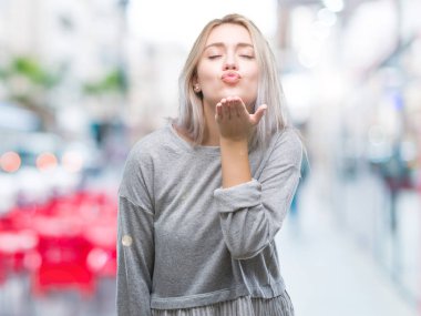 Sarışın genç kadın bir öpücük el ile güzel ve seksi olmak hava üfleme kamera bakarak izole arka plan üzerinde. Aşk ifade.