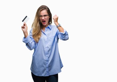 Genç güzel sarışın kadın holding kredi kartı izole üzerinde arka plan ile öfke, çılgın ve yükseltilmiş eliyle diye bağıran rahatsız ve hayal kırıklığına uğramış öfke kavramı bağırarak