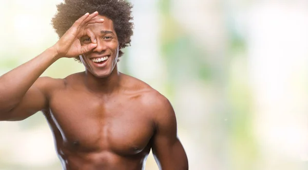 Afro american shirtless man showing nude body over isolated background doing ok gesture with hand smiling, eye looking through fingers with happy face.