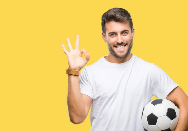 優秀なシンボルの指で サインをして孤立した背景にサッカー サッカー ボールを保持している若いハンサムな男 — ストック写真