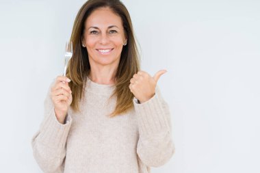 Gümüş çatal metal işaret ve başparmak kadar mutlu yüz gülümseyen tarafı ile gösteren izole arka plan üzerinde tutan orta yaş kadın