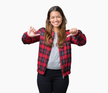 Yüzünde gülümseme ile kendinden emin görünüyorsun, kendini gururlu ve mutlu parmakları ile işaret izole arka plan üzerinde bir ceket giyen genç güzel esmer kadın.