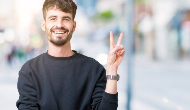 Mutlu yüz zafer işareti yaparken kameraya göz kırpıyor ile gülümseyen izole arka plan üzerinde genç yakışıklı adam. İki numaralı.