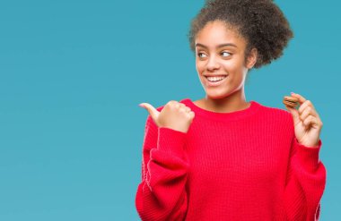 Genç afro Amerikalı kadın işaret ve başparmak kadar mutlu yüz gülümseyen tarafı ile gösteren izole arka plan üzerinde çikolata macaron yeme