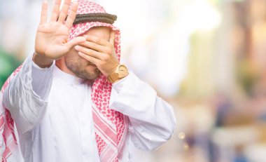 Keffiyeh üzerinde giyen genç yakışıklı adam izole elleriyle gözlerini kapsayan arka plan ve stop jest ile acı ve korku ifadesi. Utandım ve negatif kavramı.