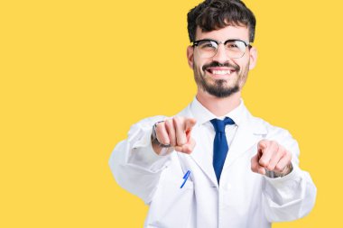 Beyaz önlük üzerinde izole giyen genç profesyonel bilim adam arka plan size işaret ve parmaklar, kamerayla olumlu ve neşeli gülümseyen
