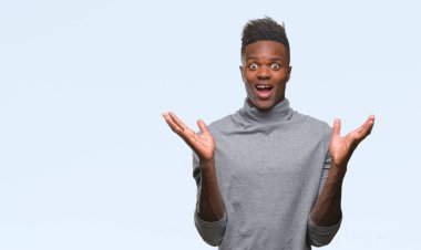 Afrikalı-Amerikalı genç deli kutluyor ve silah ile başarı için heyecanlı çığlık kaldırdı ve açık gözleri hayret izole arka plan üzerinde. Kazanan kavramı