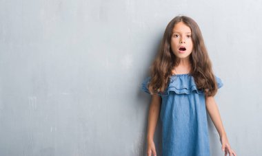 Grunge gri duvar korkuyor ve şok sürpriz ifade, korku ve heyecan yüz genç İspanyol çocuk.