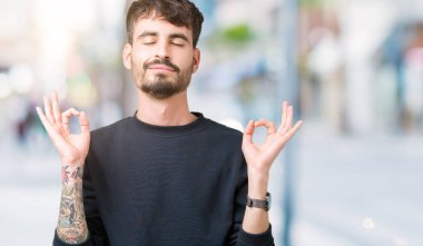 Yakışıklı delikanlı izole arka plan üzerinde dinlenmek ve gülümseyen gözlerle parmak ile meditasyon jest yapıyor kapalı. Yoga kavramı.