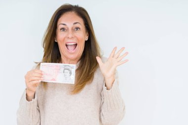 50 pound banknot büyük gülümseme ile çığlık zaferini kutluyor ve ellerini kaldırdı izole arka plan çok mutlu ve heyecanlı, kazanan ifade üzerinde tutan orta yaş kadın