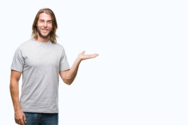 Neşeli sunulması ve kameraya bakarak avucunun ile işaret gülümseyen izole arka plan üzerinde uzun saçlı yakışıklı delikanlı.