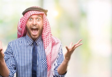 Keffiyeh üzerinde giyen genç yakışıklı Arap iş adamı deli kutluyor arka plan izole ve başarı için kaldırdı kollarını açarak hayrete ve heyecanlı çığlık gözleri açık. Kazanan kavramı