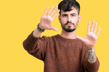 Genç yakışıklı adam giyen kış kazak izole üzerinde arka plan kullanarak el avuç içi ve parmaklar, kamera perspektif çerçevesini yapıyor gülen