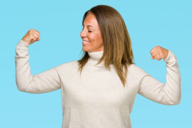 Üzerinde kış kazak giyen güzel orta yaş yetişkin kadın kol kasları gururlu gülümseyen gösterilen arka plan izole. Fitness kavramı.