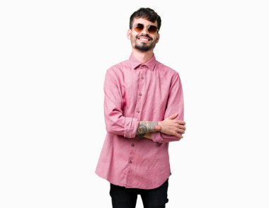 Yakışıklı delikanlı üzerinde güneş gözlüğü takıyor mutlu yüz ile gülümseyerek kameraya seyir silah geçti arka plan izole. Olumlu bir kişi.