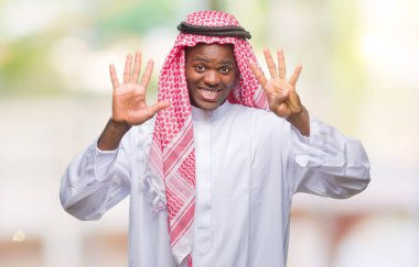 Geleneksel keffiyeh gösterilen ve parmakları ile işaret izole arka plan üzerinde giyen genç Arapça Afrika adam numara 9 kendinden emin ve mutlu gülümseyerek süre.