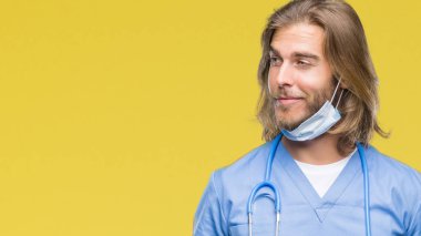 Genç yakışıklı adam uzun saçlı görünümlü yan ve dik dik bakma uzağa düşünce gülümseyen izole arka plan üzerinde doktor..