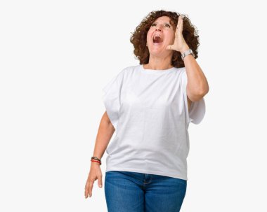 Bağırarak ve ağzı üzerinde el ile yan için çığlık izole arka plan üzerinde beyaz t-shirt giyen güzel orta ager kadın kıdemli. İletişim kavramı.