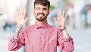 Gösterilen ve parmakları ile işaret izole arka plan üzerinde pembe gömlek giymiş genç yakışıklı adam kendinden emin ve mutlu gülümseyerek süre on numara.