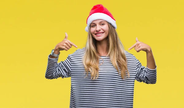 若くてきれいな金髪女性の顔に笑顔と自信を持って 誇りと幸せな指で自分を指している孤立した背景にクリスマスの帽子をかぶって — ストック写真