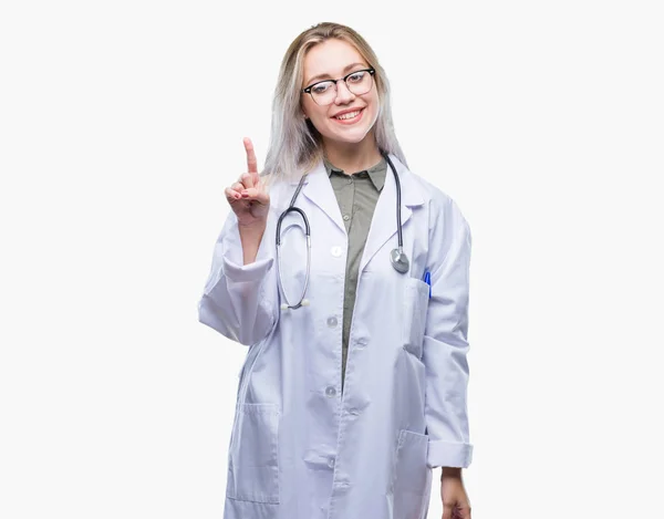 年轻的金发碧眼的医生妇女在孤立的背景显示和手指第一指向 而微笑着自信和快乐 — 图库照片