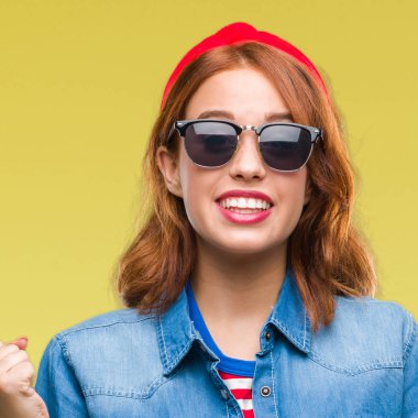 Genç güzel kadın kutluyor güneş gözlüğü takıyor izole arka plan yüzünden şaşırttı ve silah ile başarı için yükseltilmiş ve açık gözler hayrete düşürdü. Kazanan kavramı.