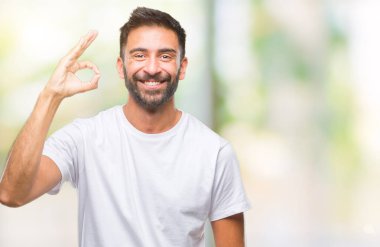 Gülümseyen izole arka plan üzerinde yetişkin İspanyol adam el ve parmaklar ok işaretiyle yapıyor olumlu. Başarılı ifade.