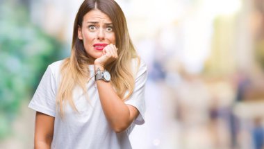 Genç güzel kadın rahat beyaz t-shirt stresli ve gergin ağız ısırma el ile izole arka plan üzerine çivi. Anksiyete sorunu.