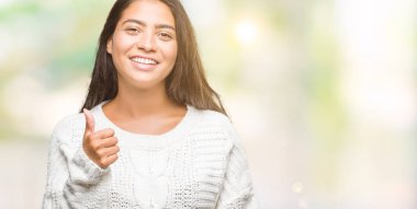 Hareketi el ile mutlu yaşasın yapıyor izole arka plan üzerinde kış kazak giyen genç güzel Arap kadın. Kameraya bakarak başarı gösteren ile ifade onaylama.