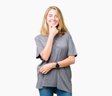 Emin çapraz kollar ve çeneme kaldırdı el ile gülümseme ile kameraya bakarak izole arka plan üzerinde büyük boy rahat t-shirt giyen güzel ve genç birbayan. Pozitif düşünce.