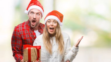 Noel şapka ve büyük gülümseme ile çığlık zaferini kutluyor ve ellerini kaldırdı izole arka plan çok mutlu ve heyecanlı, kazanan ifade üzerinde mevcut tutarak aşık genç çift