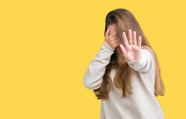 Üzerinde boğazlı kazak giyen genç güzel esmer kadın izole elleriyle gözlerini kapsayan arka plan ve stop jest ile acı ve korku ifadesi. Utandım ve negatif kavramı.