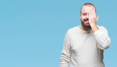 Üzerinde kış kazak giyen genç beyaz hipster adam arka plan kapsayan bir göz yüz ve sürpriz duygu kendinden emin gülümseme ile el ile izole.