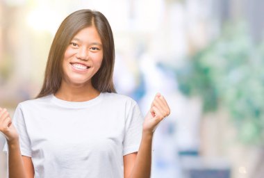 Genç Asyalı kadın kutluyor izole arka plan üzerinde şaşırttı ve başarı için kaldırdı kollarını açarak hayret ve gözleri açık. Kazanan kavramı.