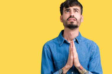 Yakışıklı delikanlı yalvarıyor ve umut ifade yüzünde çok duygusal ve endişe ile birlikte elleriyle dua izole arka plan üzerinde. Bağışlanmak. Din kavramı.