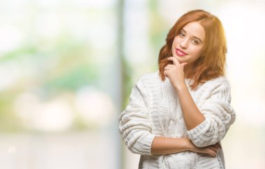 İzole arka plan emin çapraz kollar ve çeneme kaldırdı el ile gülümseme ile kameraya bakarak kış kazak giyen genç güzel kadın. Pozitif düşünce.