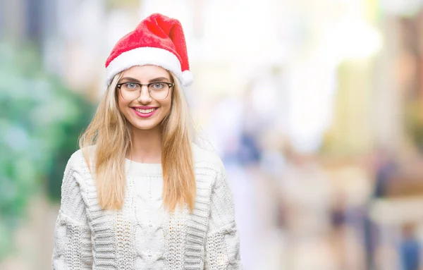 年轻美丽的金发女子戴着圣诞节帽子在孤立的背景与一个愉快和凉爽的笑容在脸上 幸运的人 — 图库照片