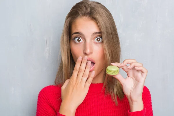 Vacker Ung Kvinna Över Grunge Grå Vägg Äta Gröna Macaron — Stockfoto