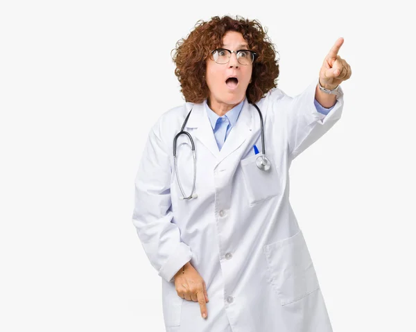 中间的资深医生妇女在孤立的背景指向用手指惊讶向前 张开嘴惊讶的表情 在前面的东西 — 图库照片