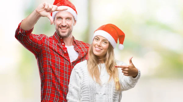 笑顔の幸せそうな顔で指と手作りフレーム分離の背景にクリスマスの帽子をかぶっての愛の若いカップル 創造性と写真のコンセプト — ストック写真