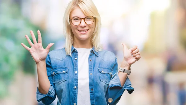 Young beautiful blonde woman wearing glasses over isolated background showing and pointing up with fingers number six while smiling confident and happy.