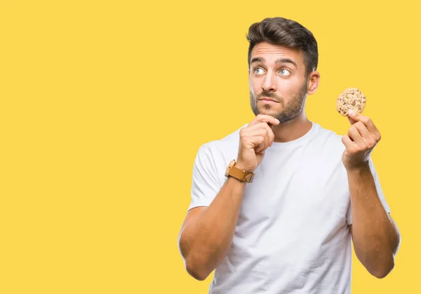 Jonge Knappe Man Eten Chocolade Chips Cookie Geïsoleerde Achtergrond Ernstige — Stockfoto