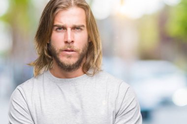 Yakışıklı delikanlı izole arka plan şüpheci ve sinir, onaylamayan ifade yüz çapraz kolları olan uzun saçlı. Negatif kişi.