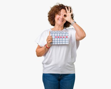 Adet takvim ile mutlu yüz el parmaklarının arasından seyir göz üzerinde ok işaretiyle yapıyor gülümseyen izole arka plan üzerinde tutan orta ager üst düzey kadın