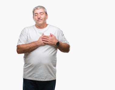 Göğüs kapalı gözler ve yüzünde minnettar jest ile üst düzey yakışıklı ile gülümseyen izole arka plan üzerinde eller. Sağlık kavramı.