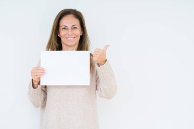 Boş kağıt sayfası işaret ve başparmak kadar mutlu yüz gülümseyen tarafı ile gösteren izole arka plan üzerinde tutan orta yaş kadın