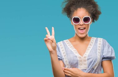 Mutlu yüz zafer işareti yaparken kameraya göz kırpıyor ile gülümseyen izole arka plan üzerinde gözlük takan genç afro Amerikalı kadın. İki numaralı.