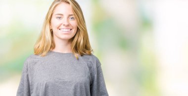 Yüzünde mutlu ve güzel bir gülümseme ile izole arka plan üzerinde büyük boy rahat t-shirt giyen güzel ve genç birbayan. Şanslı kişi.