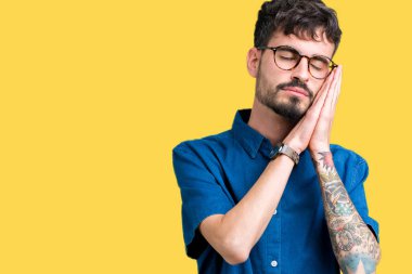 Uyku yorgun hayal ve ellerle birlikte poz ile kapalı gözler gülümseyen izole arka plan üzerinde gözlük takan genç yakışıklı adam.