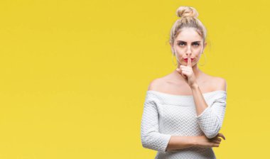 Genç güzel sarışın ve mavi gözlü kadın dudaklarında parmak ile sessiz olmanı izole arka plan yüzünden. Sessizlik ve gizli kavramı.